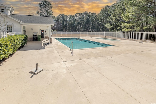 pool at dusk with a patio area