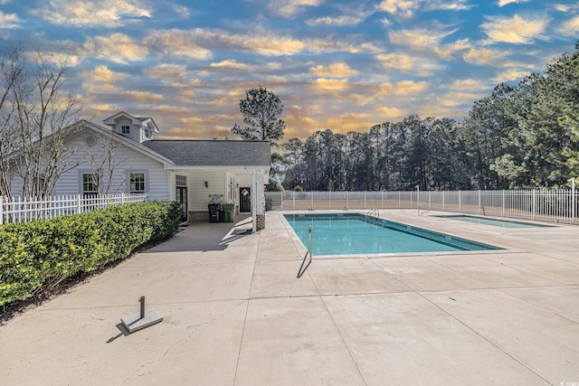 pool at dusk with a patio area