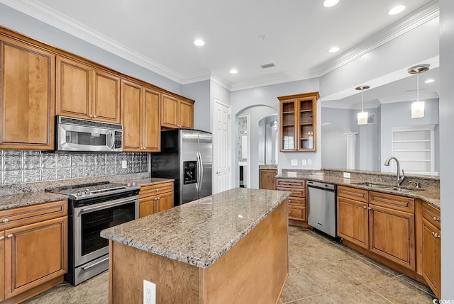 kitchen with sink, light stone counters, tasteful backsplash, a center island, and appliances with stainless steel finishes