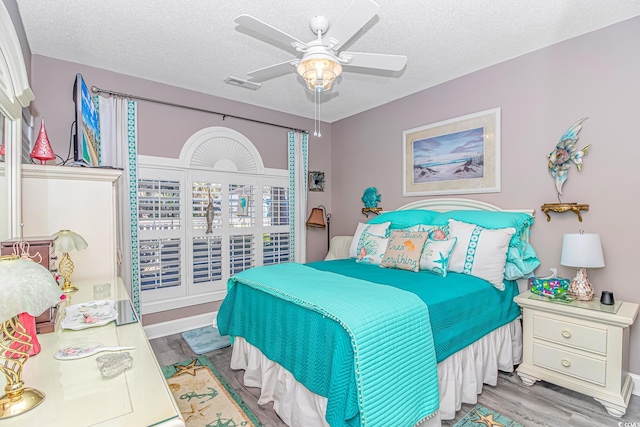 bedroom featuring ceiling fan, light hardwood / wood-style floors, and a textured ceiling