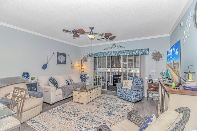 living room featuring ceiling fan, crown molding, wood-type flooring, and a textured ceiling