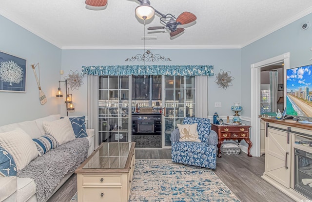 living room with ceiling fan, ornamental molding, and a textured ceiling