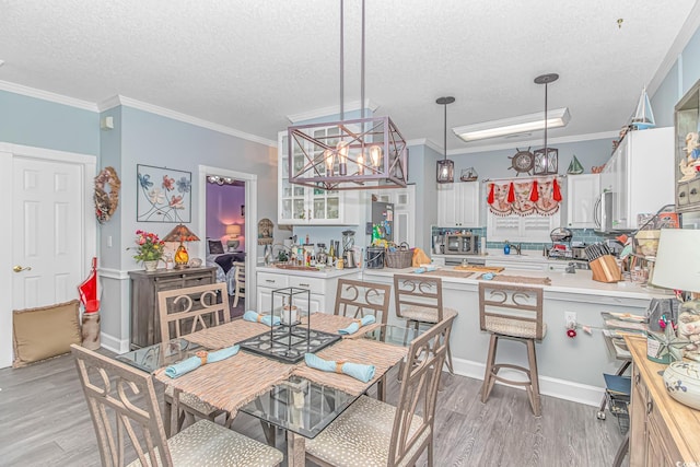 dining area featuring hardwood / wood-style flooring, ornamental molding, a textured ceiling, and a notable chandelier