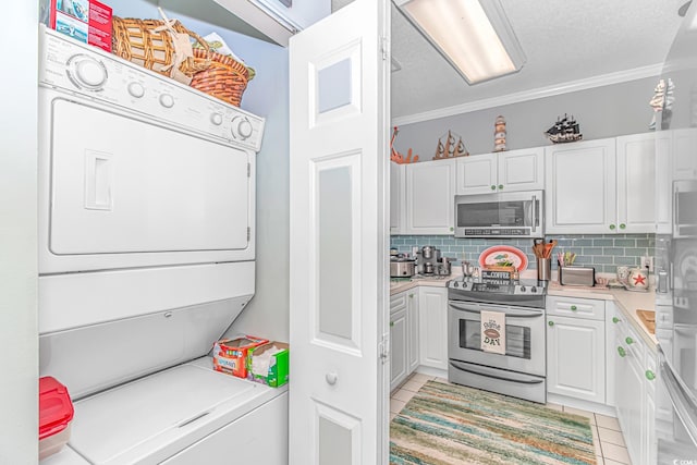 clothes washing area featuring crown molding, stacked washer / drying machine, light tile patterned flooring, and a textured ceiling