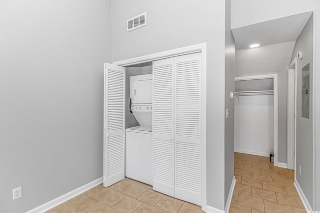 washroom with laundry area, visible vents, stacked washer / dryer, and light tile patterned flooring