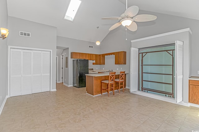 kitchen featuring brown cabinets, light countertops, visible vents, freestanding refrigerator, and a peninsula