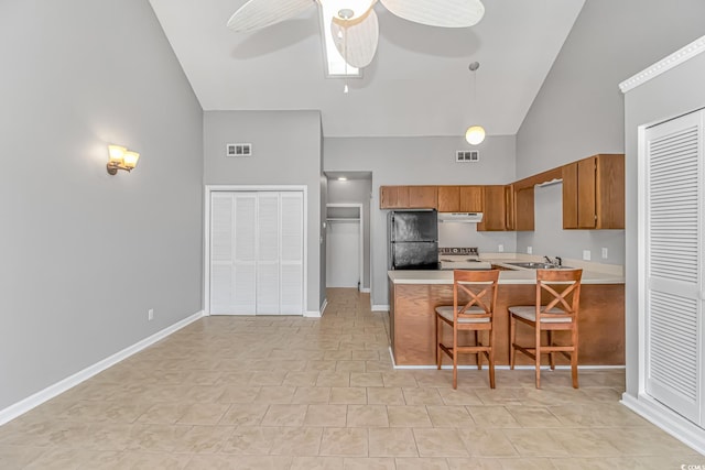 kitchen with visible vents, brown cabinetry, freestanding refrigerator, a peninsula, and light countertops