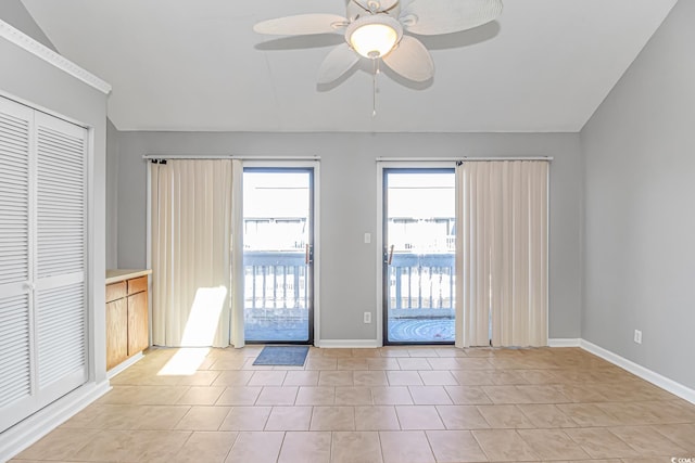 spare room with vaulted ceiling, ceiling fan, light tile patterned floors, and baseboards