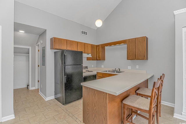 kitchen featuring brown cabinets, white electric stove, freestanding refrigerator, a peninsula, and under cabinet range hood