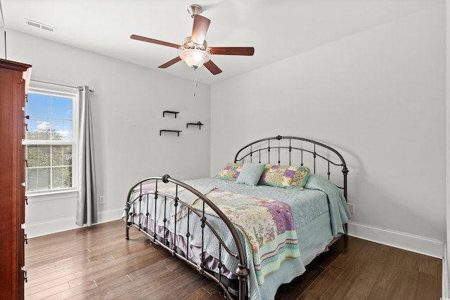 bedroom featuring multiple windows, dark wood-type flooring, and ceiling fan