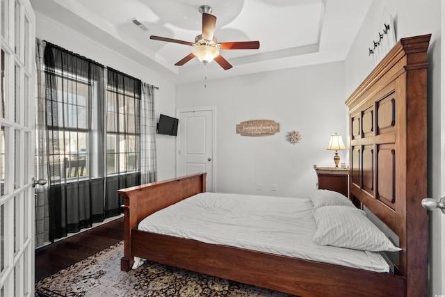 bedroom featuring hardwood / wood-style flooring, ceiling fan, and a raised ceiling