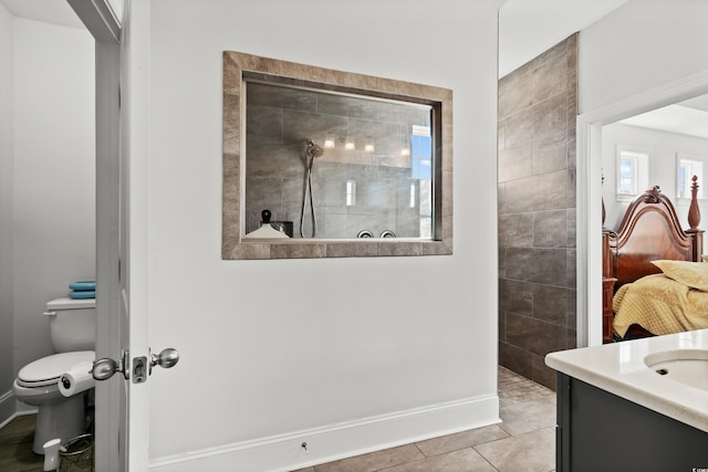 bathroom featuring vanity, tile patterned floors, toilet, and tiled shower