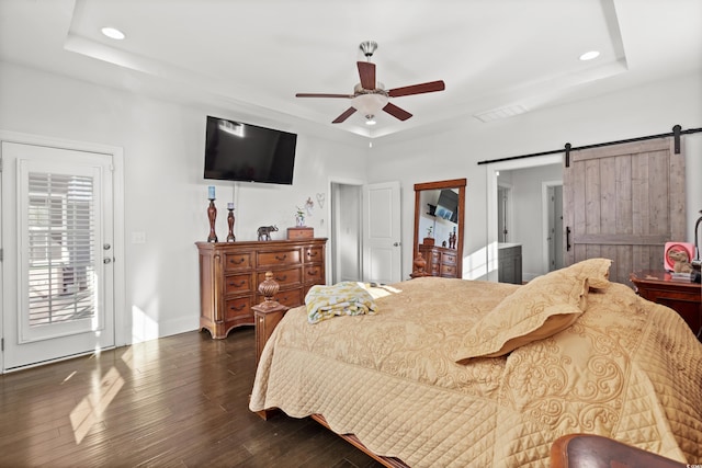 bedroom with access to outside, dark hardwood / wood-style floors, a raised ceiling, ceiling fan, and a barn door