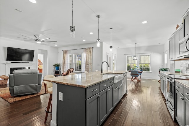 kitchen with stainless steel appliances, sink, a kitchen island with sink, and gray cabinetry