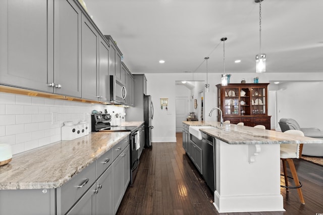 kitchen with a large island, sink, a breakfast bar area, hanging light fixtures, and stainless steel appliances