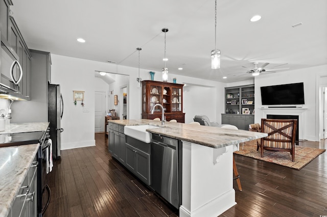 kitchen with sink, built in features, appliances with stainless steel finishes, gray cabinetry, and hanging light fixtures