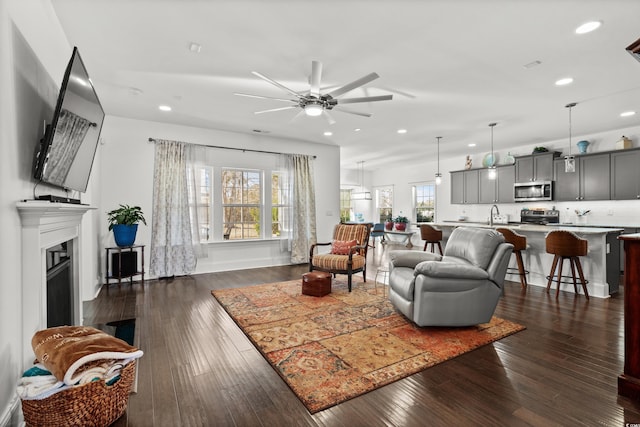 living room featuring dark hardwood / wood-style flooring, sink, and ceiling fan