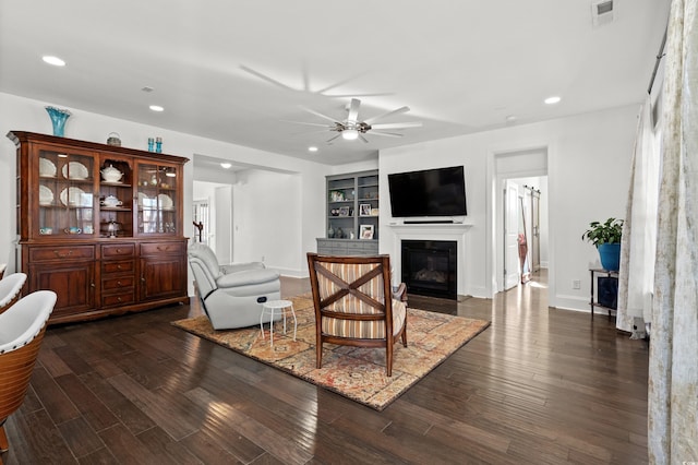 living room featuring dark hardwood / wood-style flooring, built in features, and ceiling fan