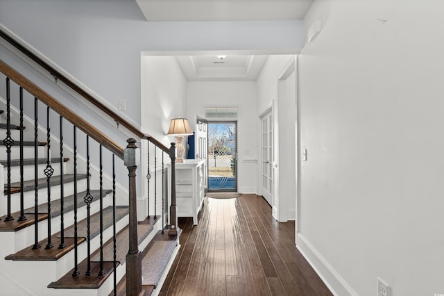 hallway featuring dark wood-type flooring and a tray ceiling