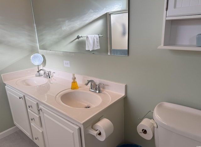 bathroom with double vanity, toilet, and a sink