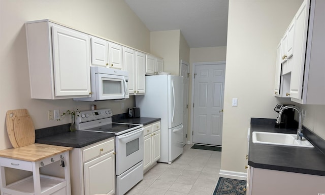 kitchen featuring white appliances, light tile patterned flooring, a sink, white cabinetry, and dark countertops