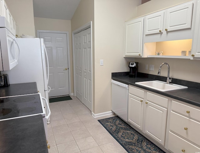 kitchen featuring dark countertops, light tile patterned flooring, white appliances, white cabinetry, and a sink