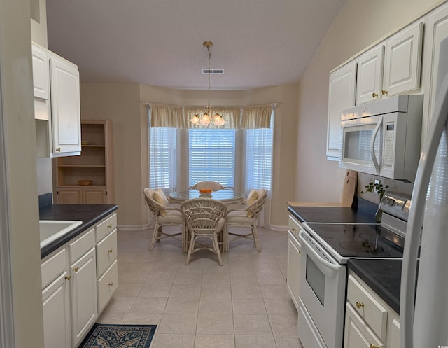 kitchen with white appliances, dark countertops, a chandelier, and white cabinets