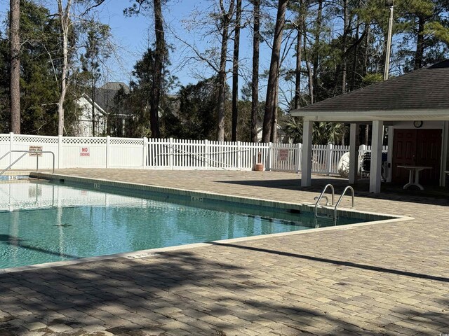 community pool with a patio and fence