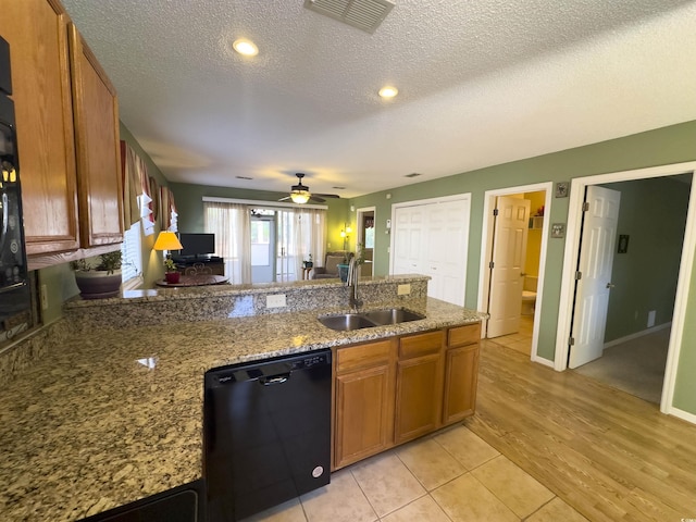 kitchen with sink, a textured ceiling, dishwasher, light stone countertops, and light hardwood / wood-style floors