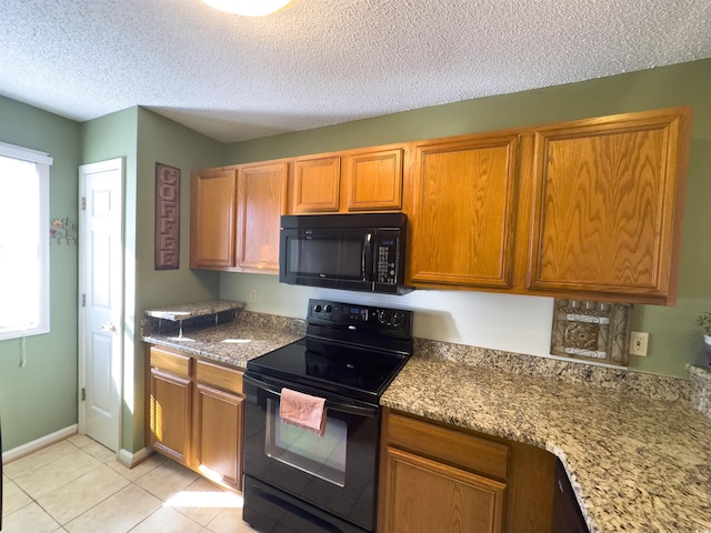 kitchen featuring light stone countertops, light tile patterned floors, black appliances, and a textured ceiling