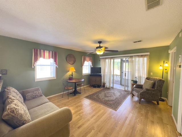 living room with a wealth of natural light, light hardwood / wood-style floors, and a textured ceiling