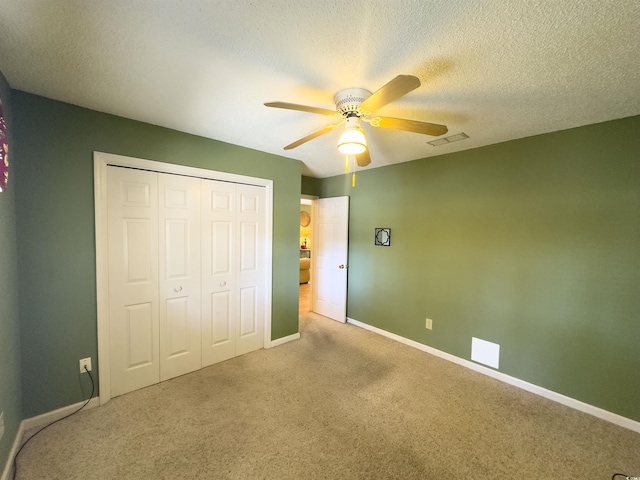 unfurnished bedroom with ceiling fan, a closet, a textured ceiling, and carpet