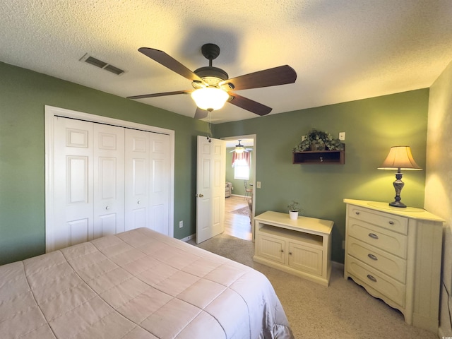 carpeted bedroom featuring ceiling fan, a closet, and a textured ceiling