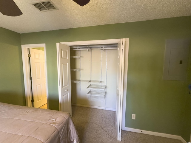 carpeted bedroom featuring ceiling fan, electric panel, a closet, and a textured ceiling