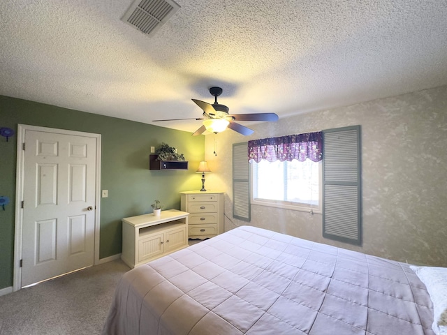 carpeted bedroom featuring ceiling fan and a textured ceiling