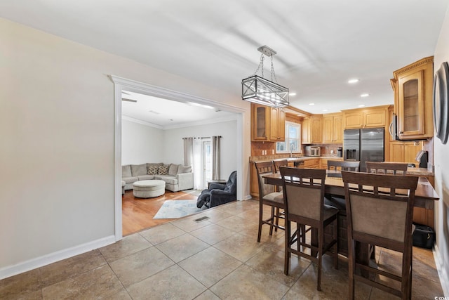 dining space featuring ornamental molding and light tile patterned floors