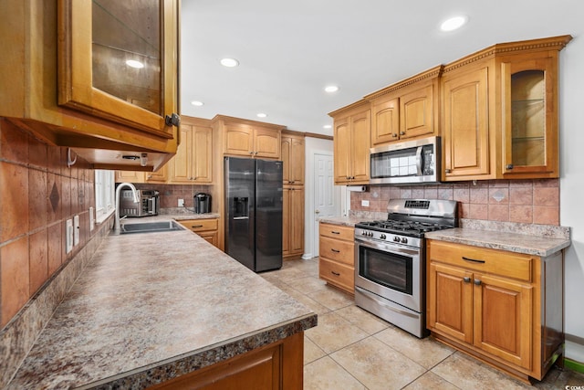 kitchen featuring sink, decorative backsplash, light tile patterned flooring, and appliances with stainless steel finishes