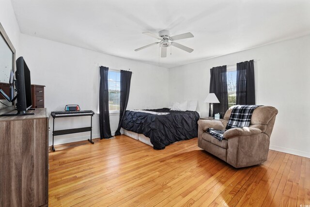 bedroom featuring ceiling fan, light hardwood / wood-style floors, and multiple windows