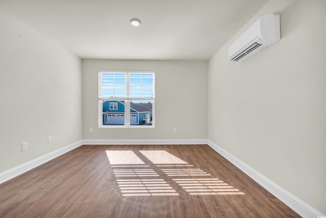 unfurnished room featuring baseboards, an AC wall unit, and wood finished floors