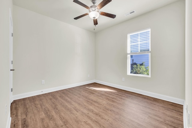 unfurnished room featuring a ceiling fan, wood finished floors, visible vents, and baseboards