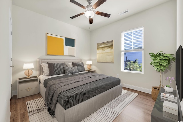 bedroom with visible vents, ceiling fan, light wood-style flooring, and baseboards