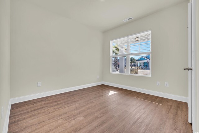 empty room with visible vents, baseboards, and wood finished floors