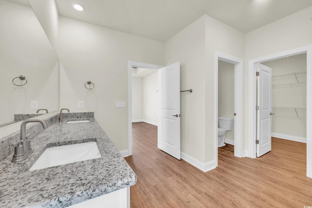 bathroom featuring baseboards, a sink, toilet, and wood finished floors