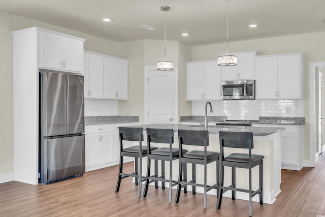 kitchen featuring stainless steel appliances, a center island with sink, and white cabinets