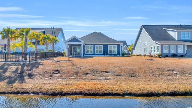 view of front of home featuring a water view, fence, and a sunroom