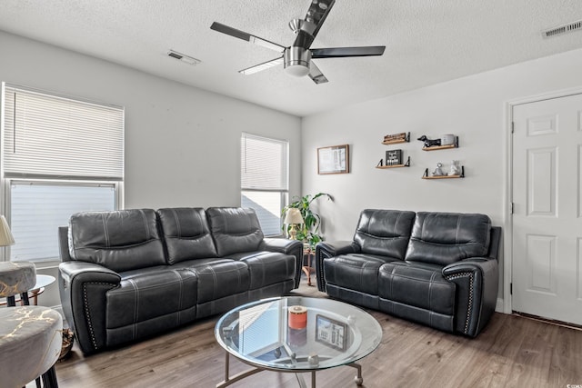 living room with wood-type flooring, a textured ceiling, and ceiling fan