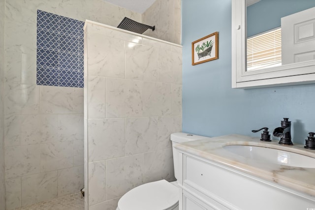 bathroom featuring vanity, a tile shower, and toilet