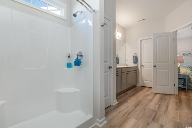 bathroom with a shower, hardwood / wood-style floors, and vanity