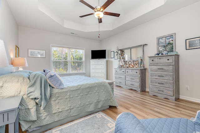 bedroom featuring a tray ceiling, light hardwood / wood-style flooring, and ceiling fan