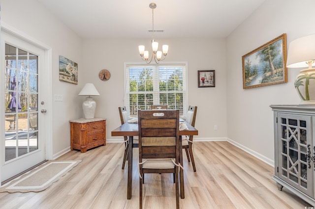 dining space with light hardwood / wood-style floors and a notable chandelier